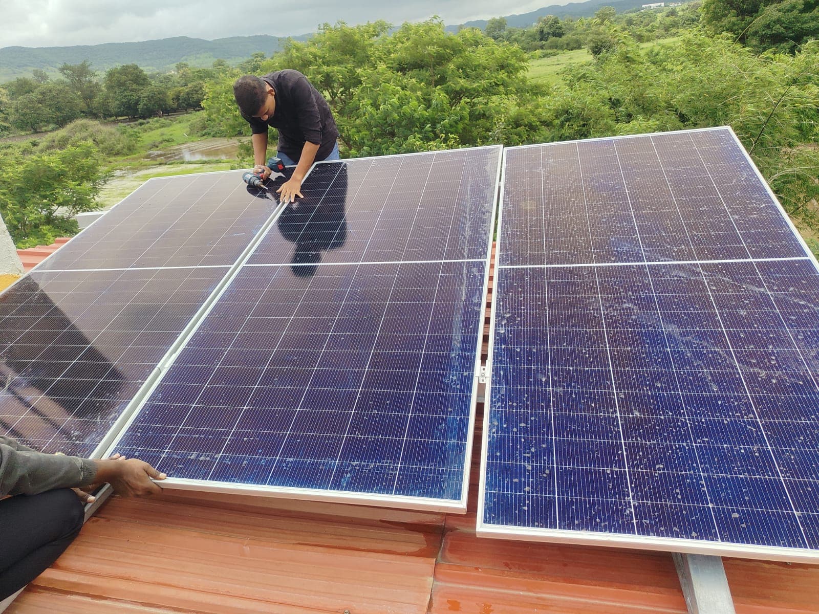 Technicians bolting solar modules onto a sheet roof in the Western Ghats